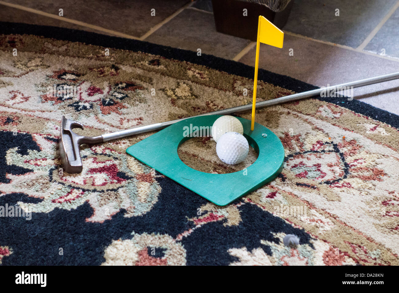 An indoor practice golf putting cup with two golf balls and a putter
