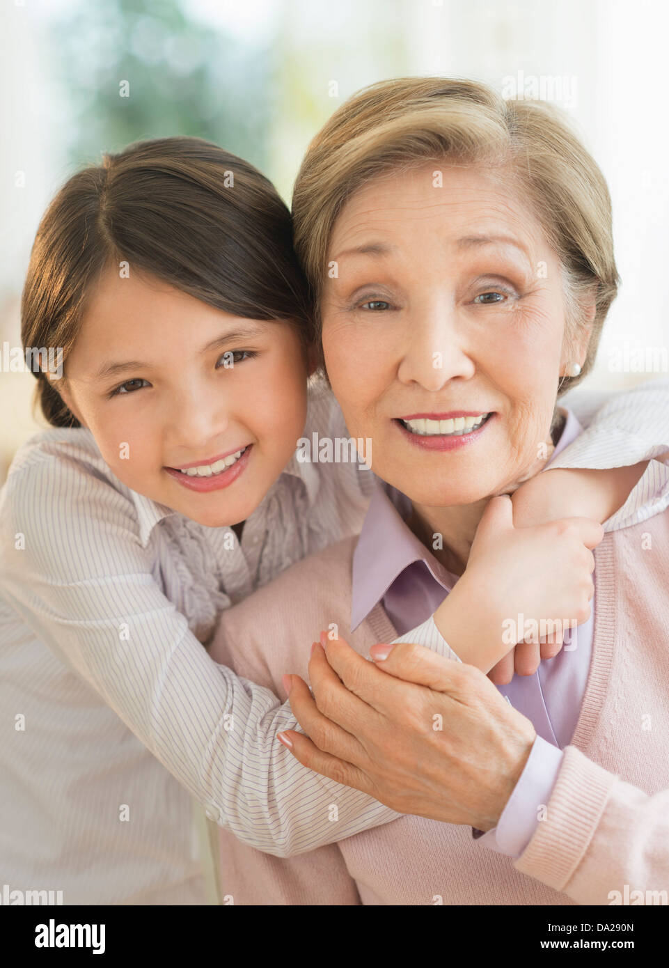 Granddaughter (8-9) embracing grandmother Stock Photo