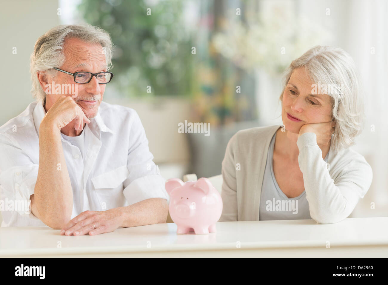 Senior couple looking at piggybank Stock Photo
