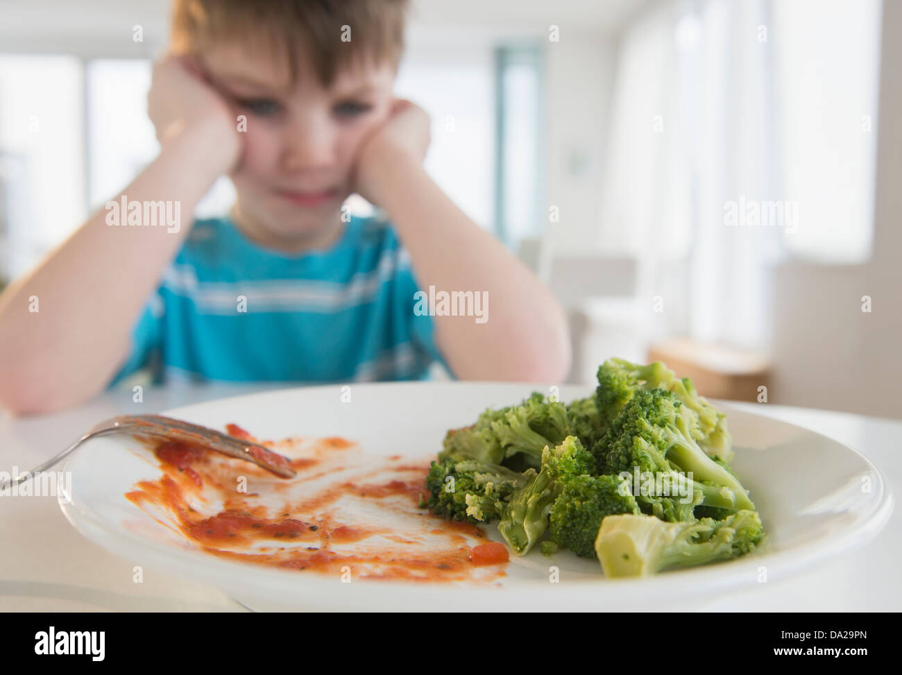 Portrait of boy (4-5) annoyed to eat broccoli Stock Photo