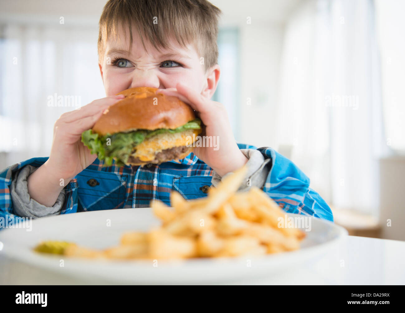 Portrait of boy (4-5) eating hamburger Stock Photo