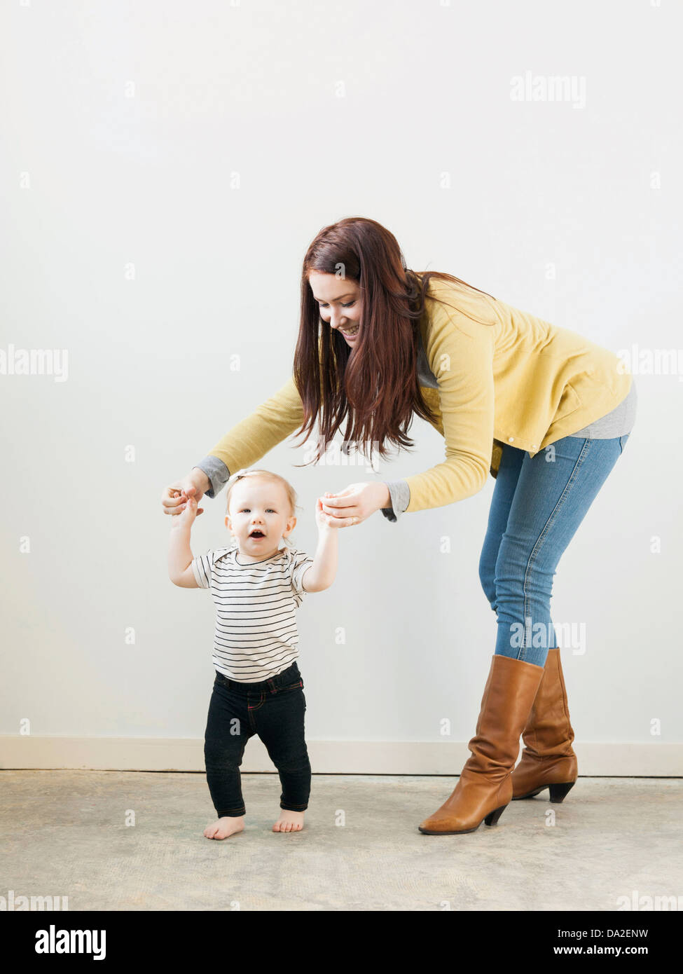 Mother helping baby daughter walk hi-res stock photography and images ...