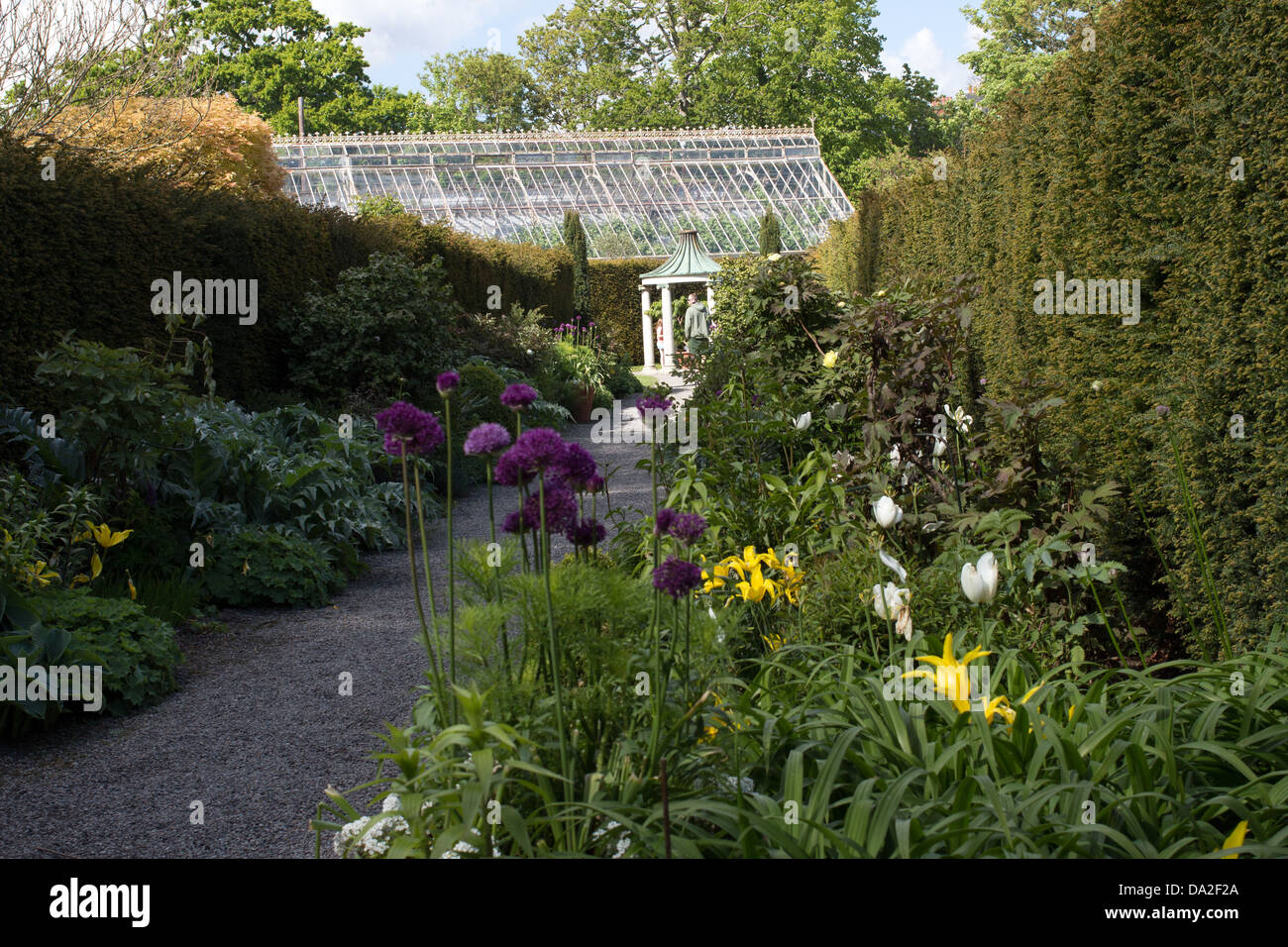 Pathway in the garden, with a green house in the background. Stock Photo