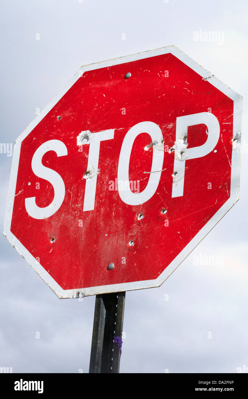 Low angle view of stop sign with bullet holes Stock Photo