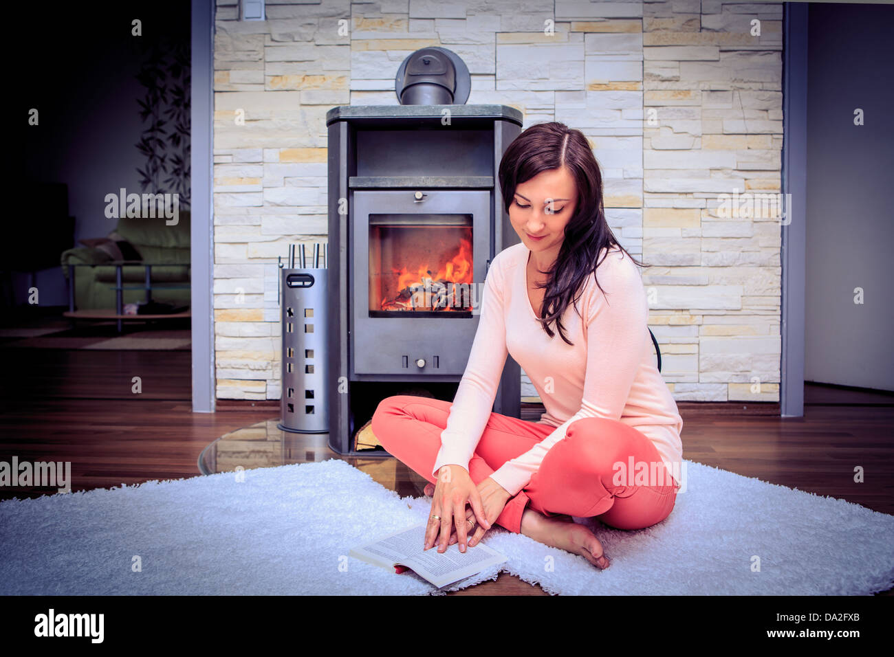 a young woman reading in front of chimney in the living room Stock Photo
