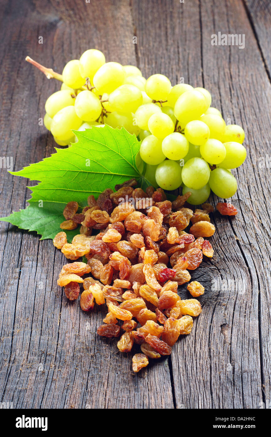 Raisins and grapes with leaves on a wooden background Stock Photo