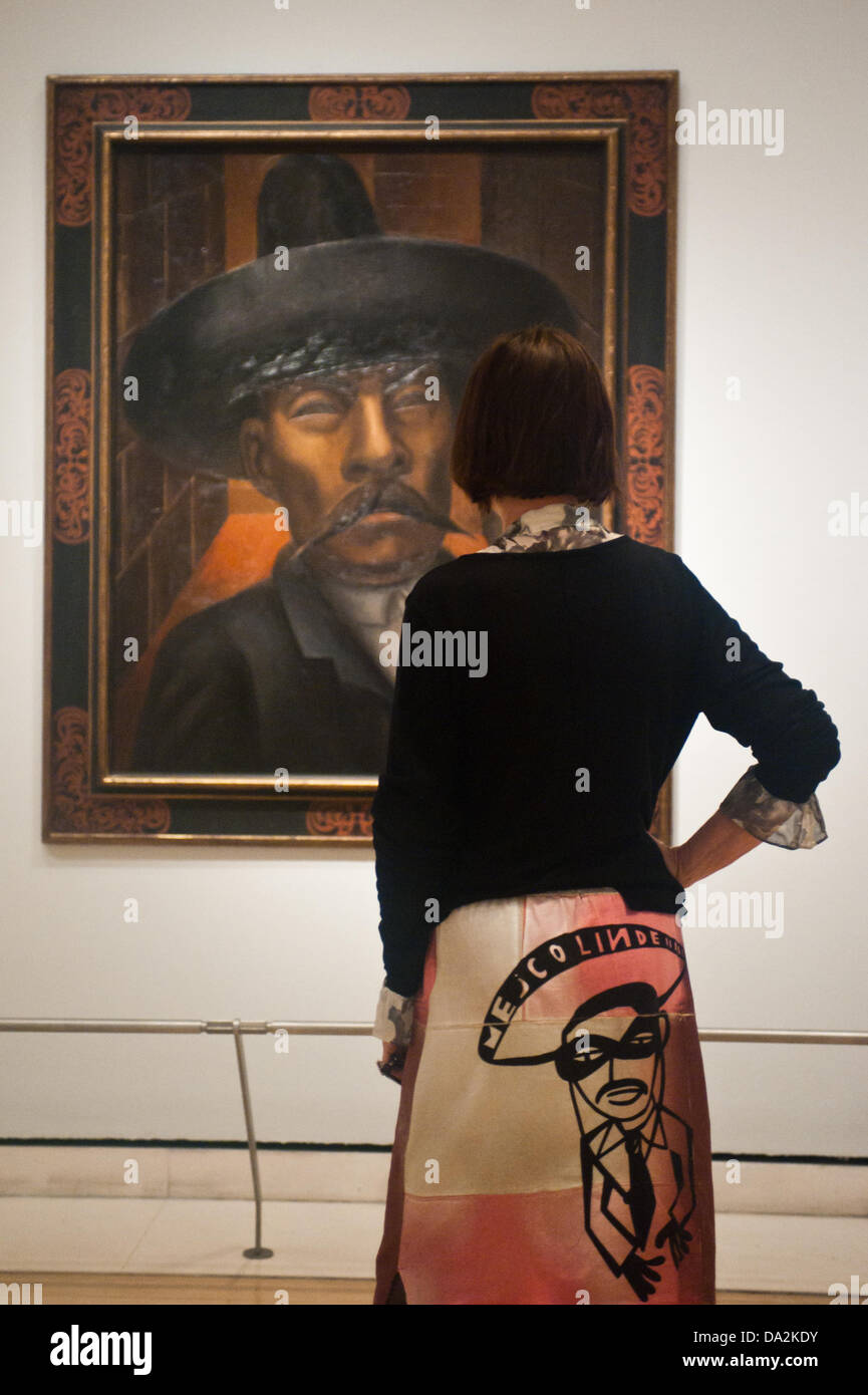 London, UK - 2 July 2013: a woman wears a skirt reading 'Mejico Lindo' and stands next to a work by David Alfaro Siqueiros at the exhibition 'Mexico: A Revolution in Art, 1910–1940' which opens at the Royal Academy of Arts on the 6th of July. The show features over 120 paintings and photographs and examines the intense period of artistic creativity that took place in Mexico at the beginning of the 20th century. Credit:  Piero Cruciatti/Alamy Live News Stock Photo