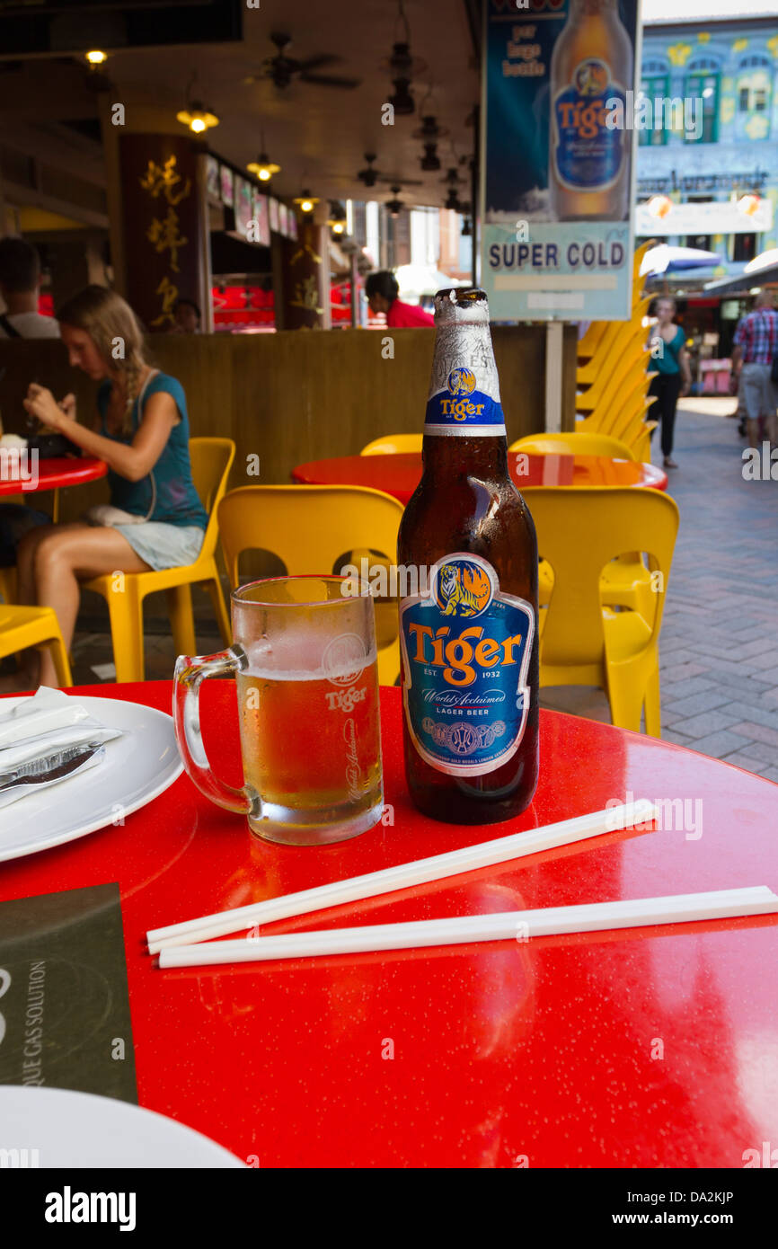 Bottle and glass of cold Tiger beer on a red table with a pair of chopsticks at a Chinese restaurant, Chinatown, Singapore Stock Photo
