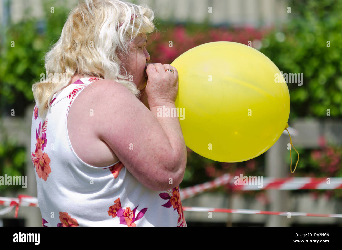Woman blowing up a yellow balloon Stock Photo