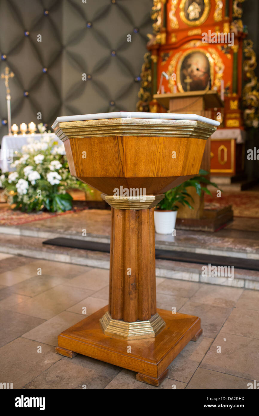 The baptismal font in the Catholic church, the altar in the background. Stock Photo