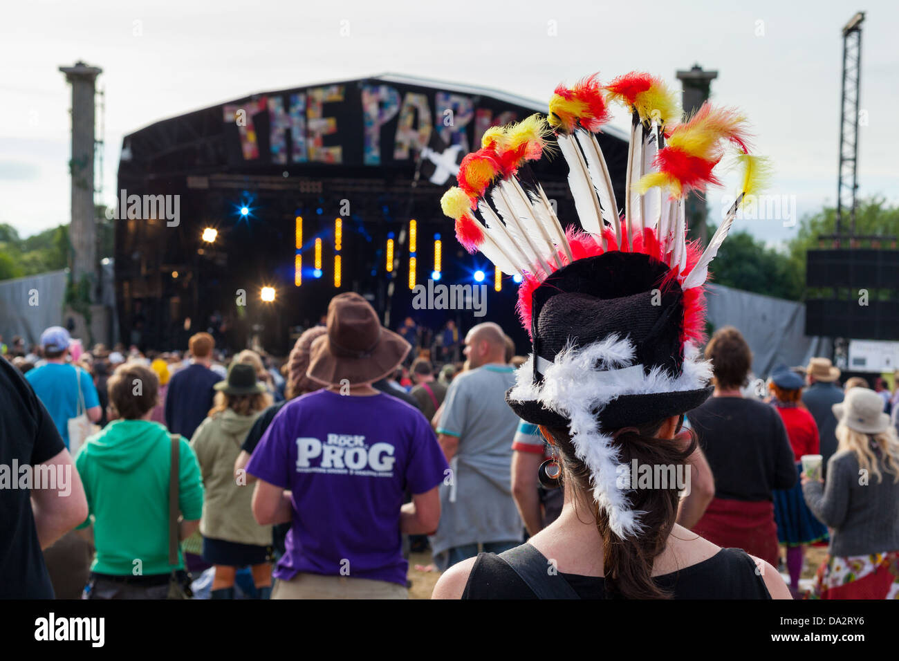 GLASTONBURY FESTIVAL, UNITED KINGDOM - JUNE 30 2013 : Back view of a woman wearing a brightly feathered hat at the Park Stage Stock Photo
