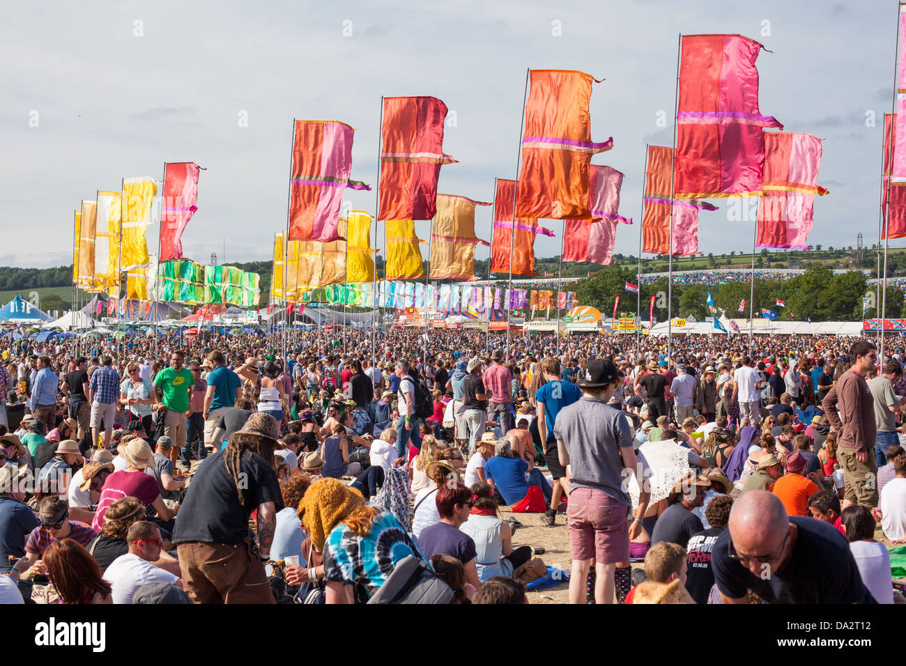 GLASTONBURY FESTIVAL, UNITED KINGDOM - JUNE 30 2013 : Crowds sit in the sunshine under the coloured flags at the Other Stage Stock Photo