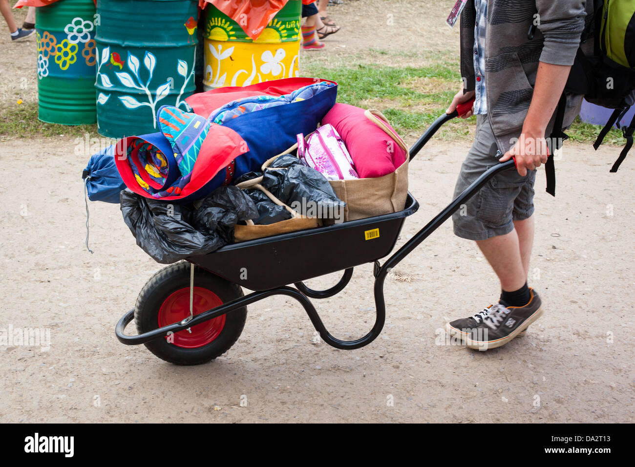 GLASTONBURY FESTIVAL, UK - JUNE 30 2013 :Anonymous man transporting camping equipment in a wheelbarrow Stock Photo