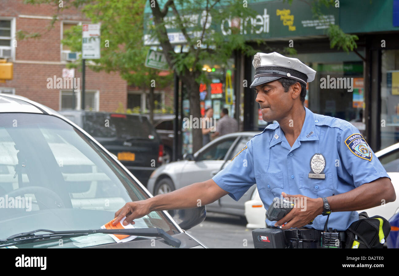 A New York City traffic policeman gives a ticket to a parked vehicle for an expired meter. In Jackson Heights, Queens, New York Stock Photo