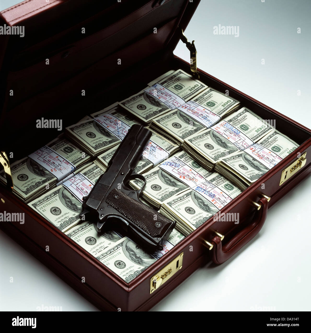 Briefcase with stacks of bundled 100 US Dollar bills and gun Stock Photo