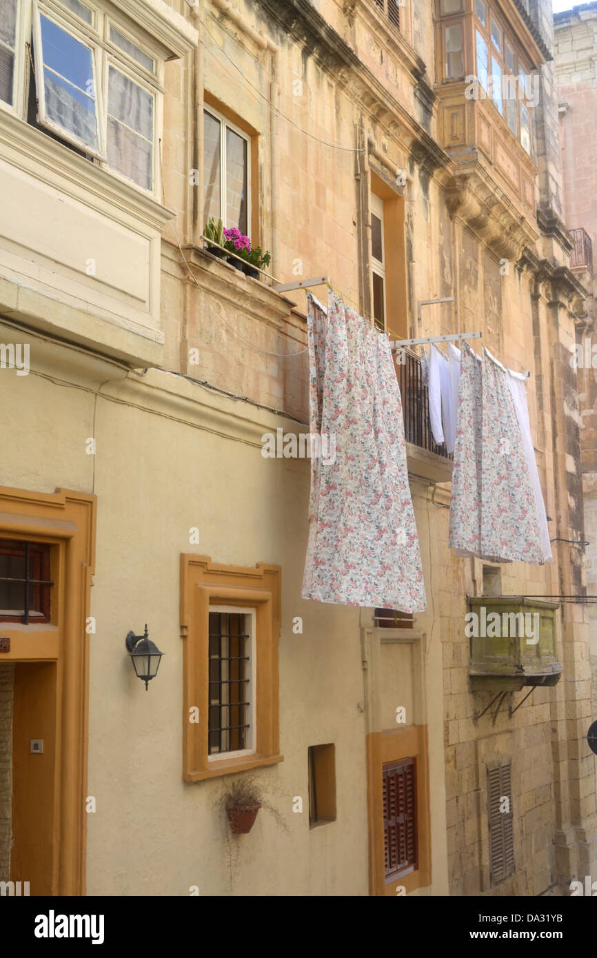 Washing hanging from apartment windows in Valletta town, Malta. Stock Photo