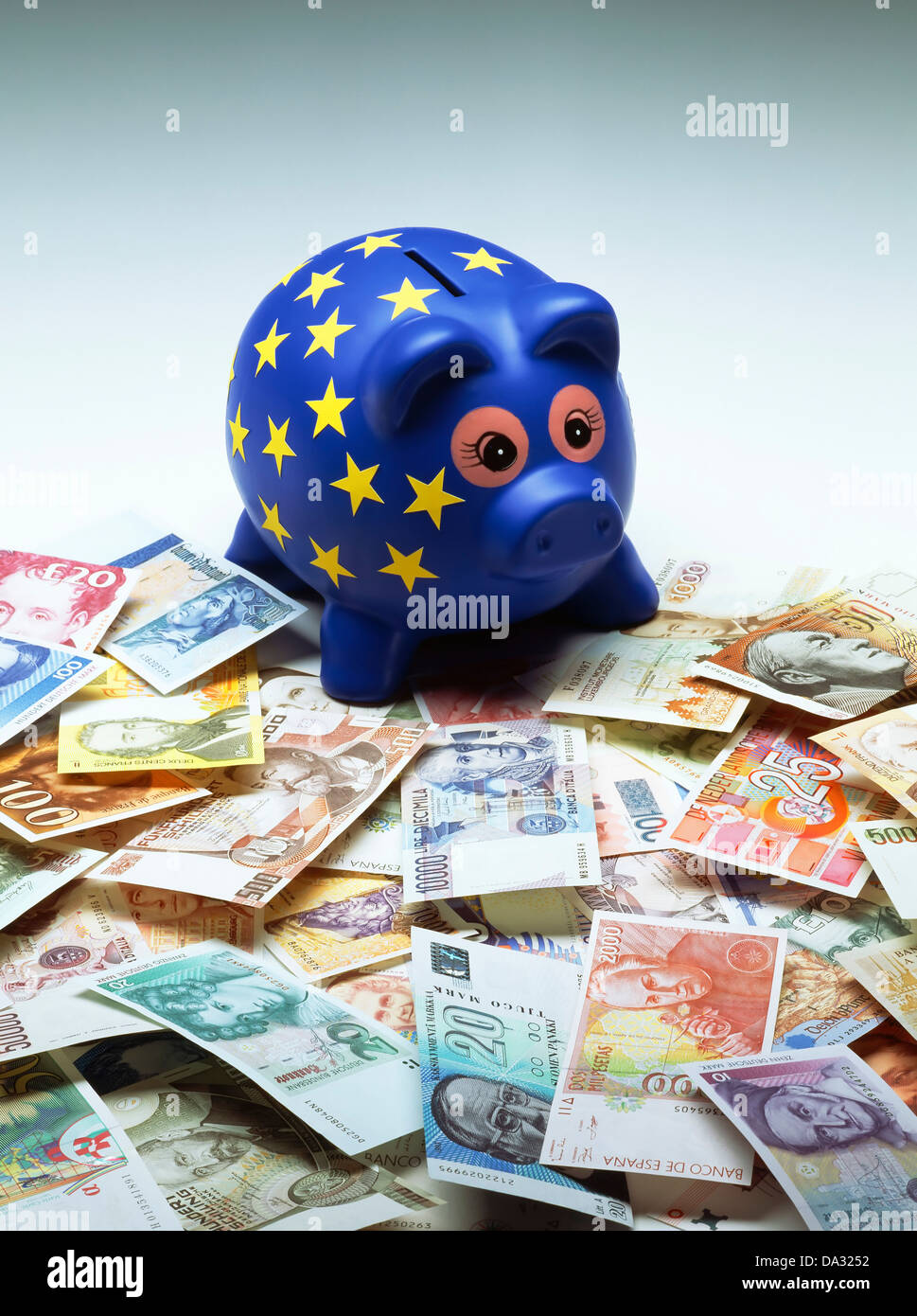 Blue European piggy bank decorated with yellow stars and former banknotes of the European countries forming the Euro Stock Photo
