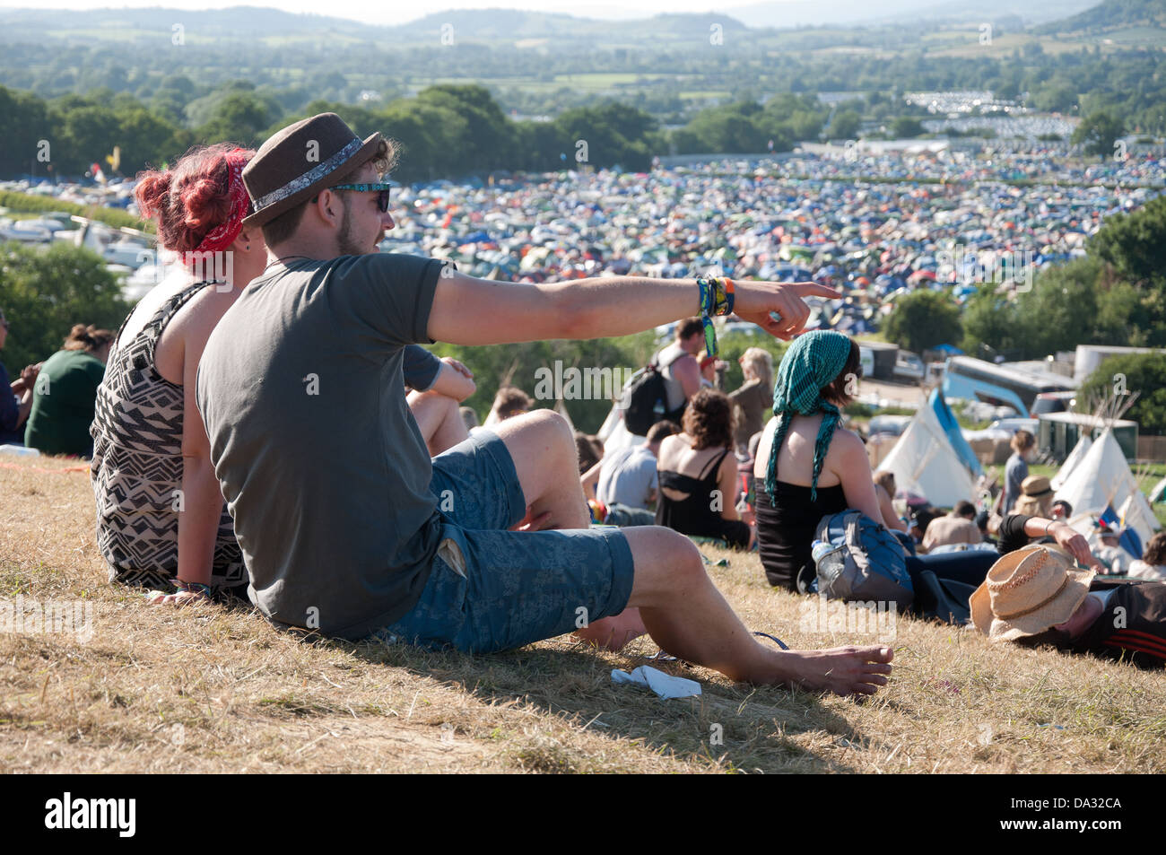 A couple sit at the top of The Park at Glastonbury Festival of Contemporary Performing Arts 2013, admiring the view. Stock Photo