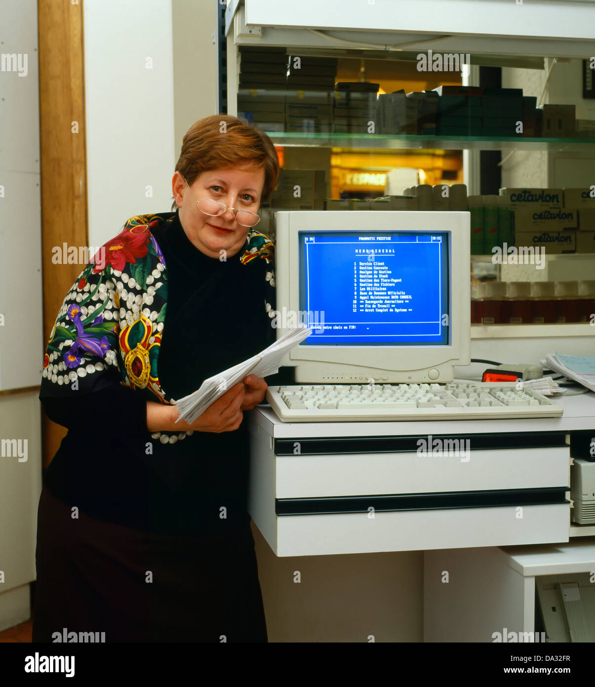 Chubby woman standing by computer, pharmacy office Stock Photo