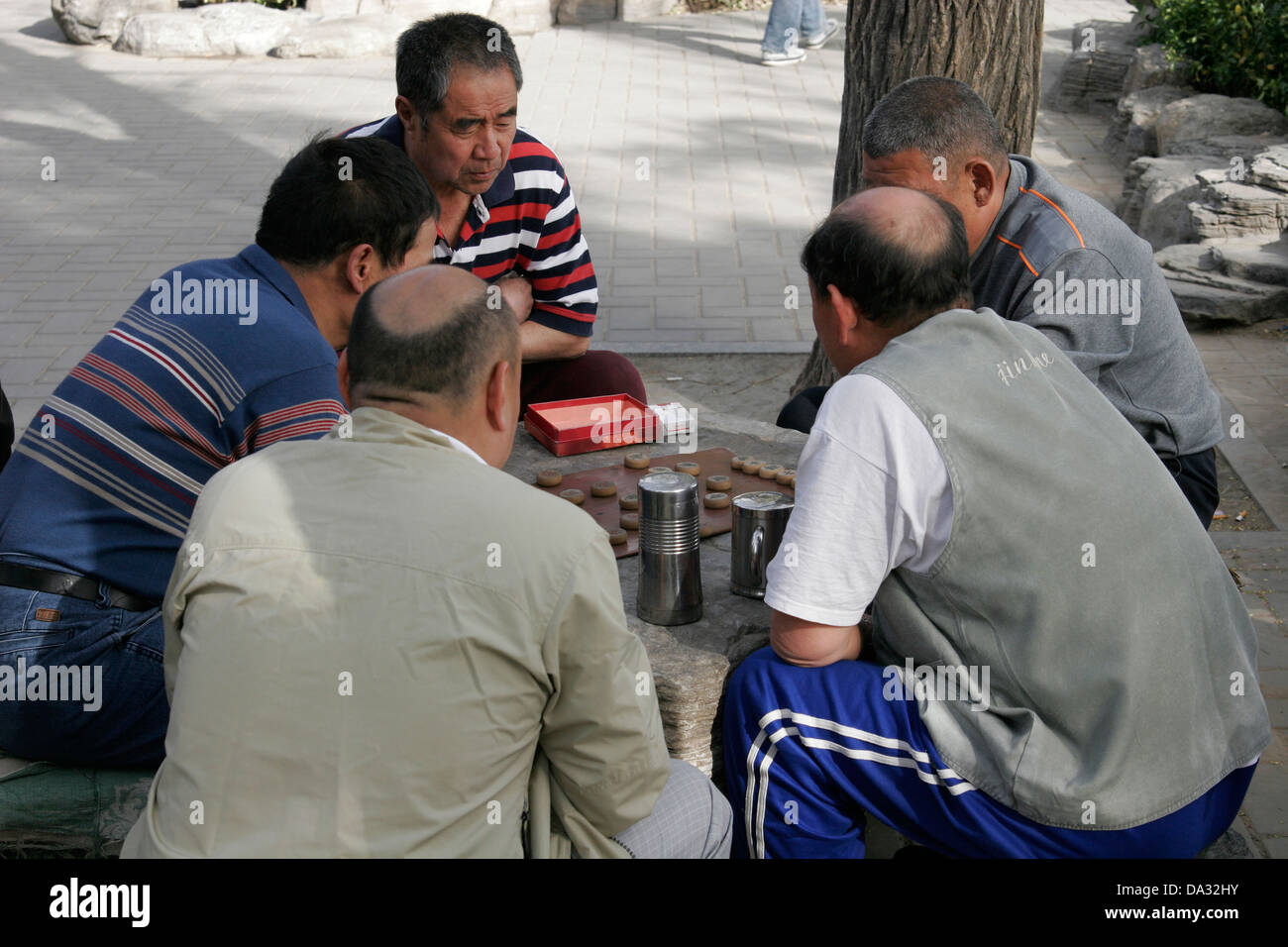 Chinese men sitting outdoors playing board game, Beijing, China Stock Photo