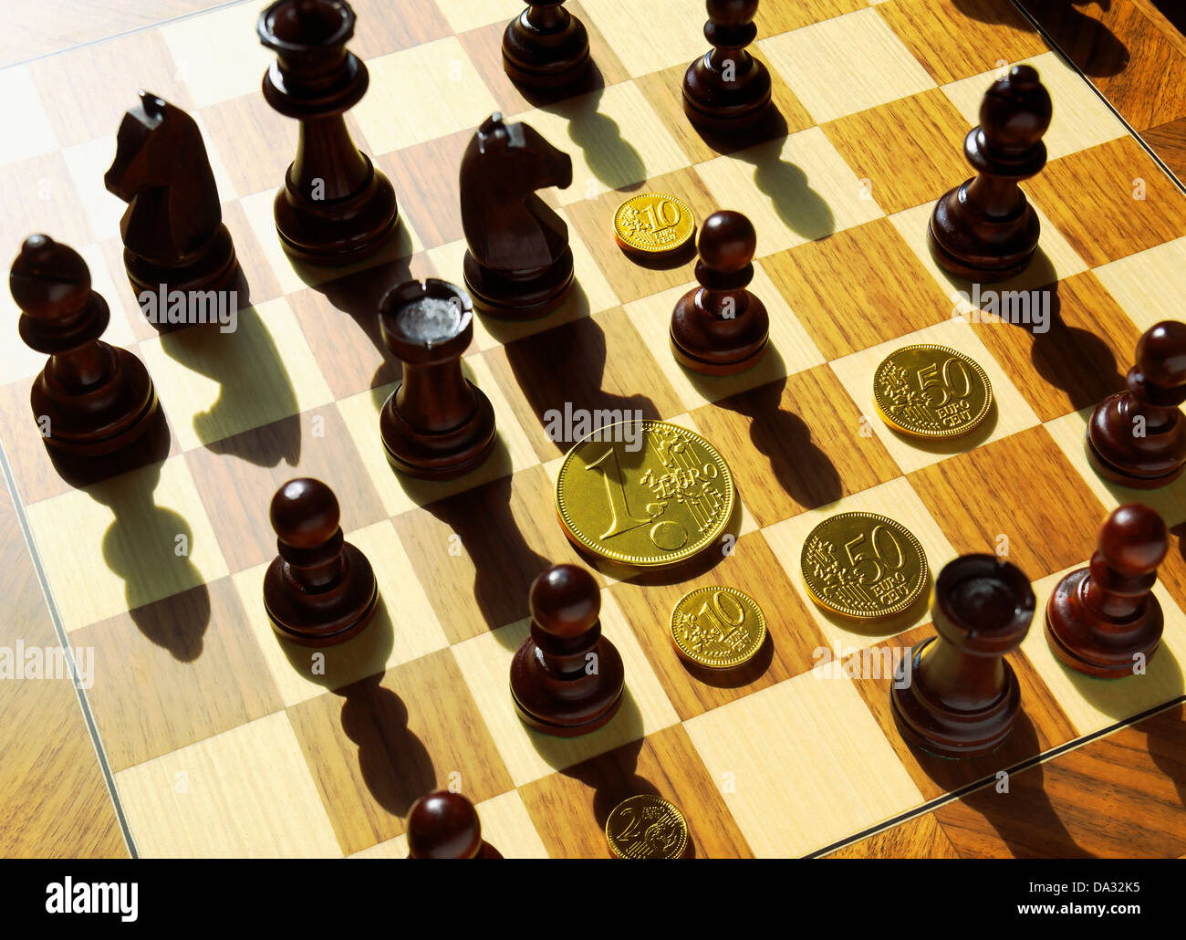 Chessmen and golden Euro coins on chessboard Stock Photo
