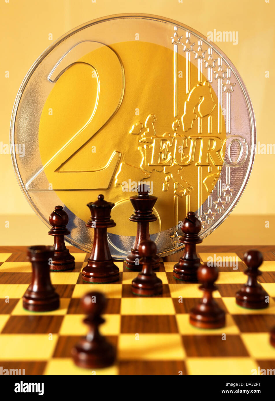 Chessmen and giant golden 2 Euro coin on chessboard Stock Photo