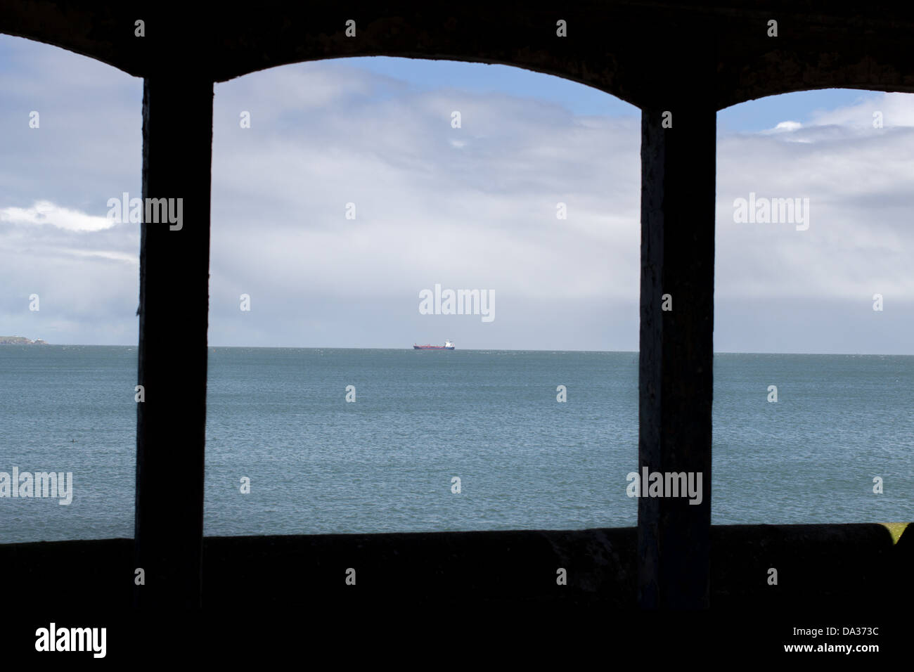 Commercial vessel seen from inside of shelter positioned by the coast. Stock Photo