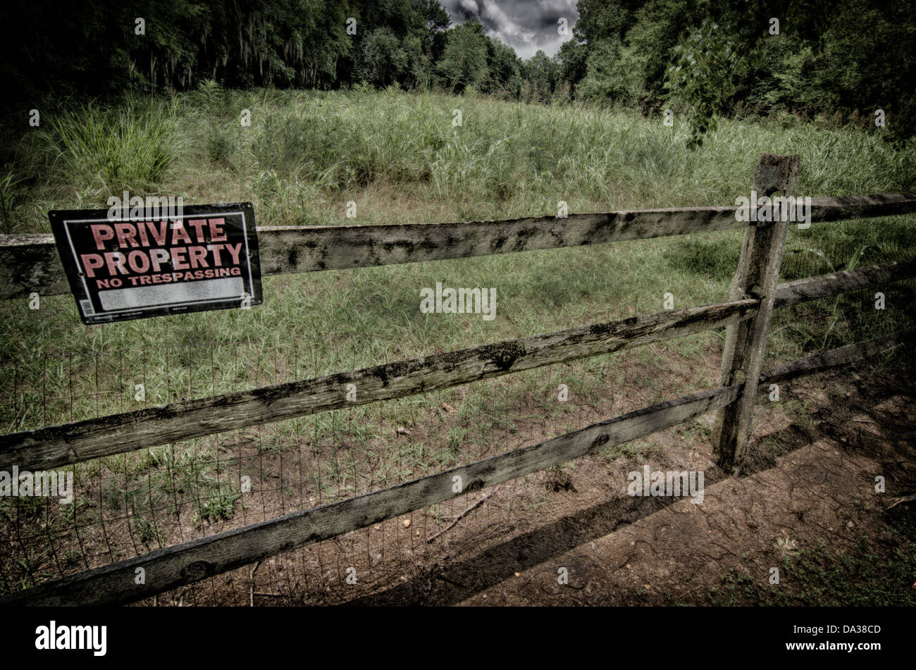 This is a grungy image of a private property sign on a wooden fence in a rural area. Stock Photo