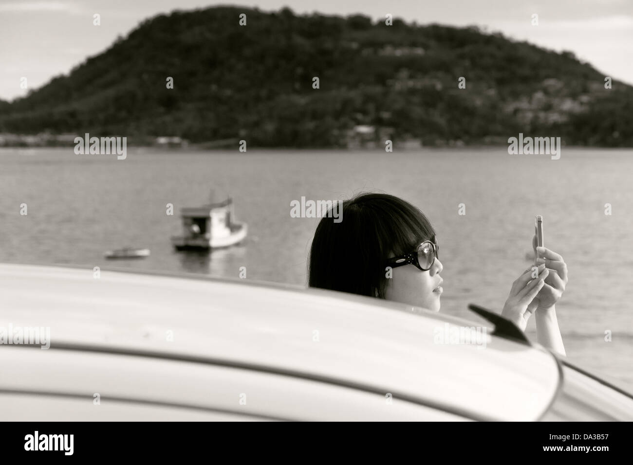 Tourist shoots sunset with mobile phone cam at Kalim Beach Stock Photo