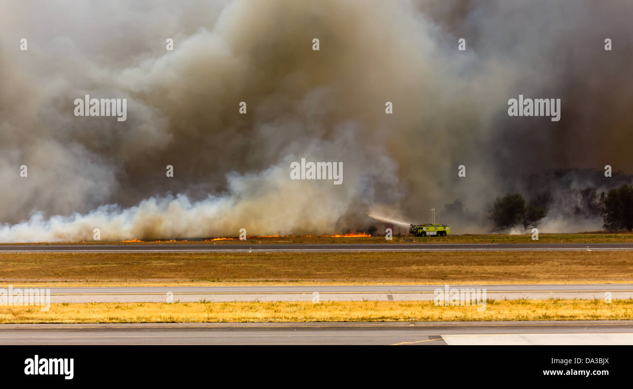 Firemen squirt water on brush wildfire that threatens San Salvador International Airport radar and control tower Stock Photo