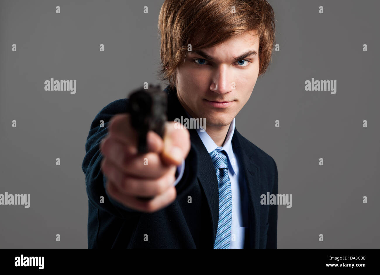 Stressed businessman holding and pointing a gun to the camera Stock Photo