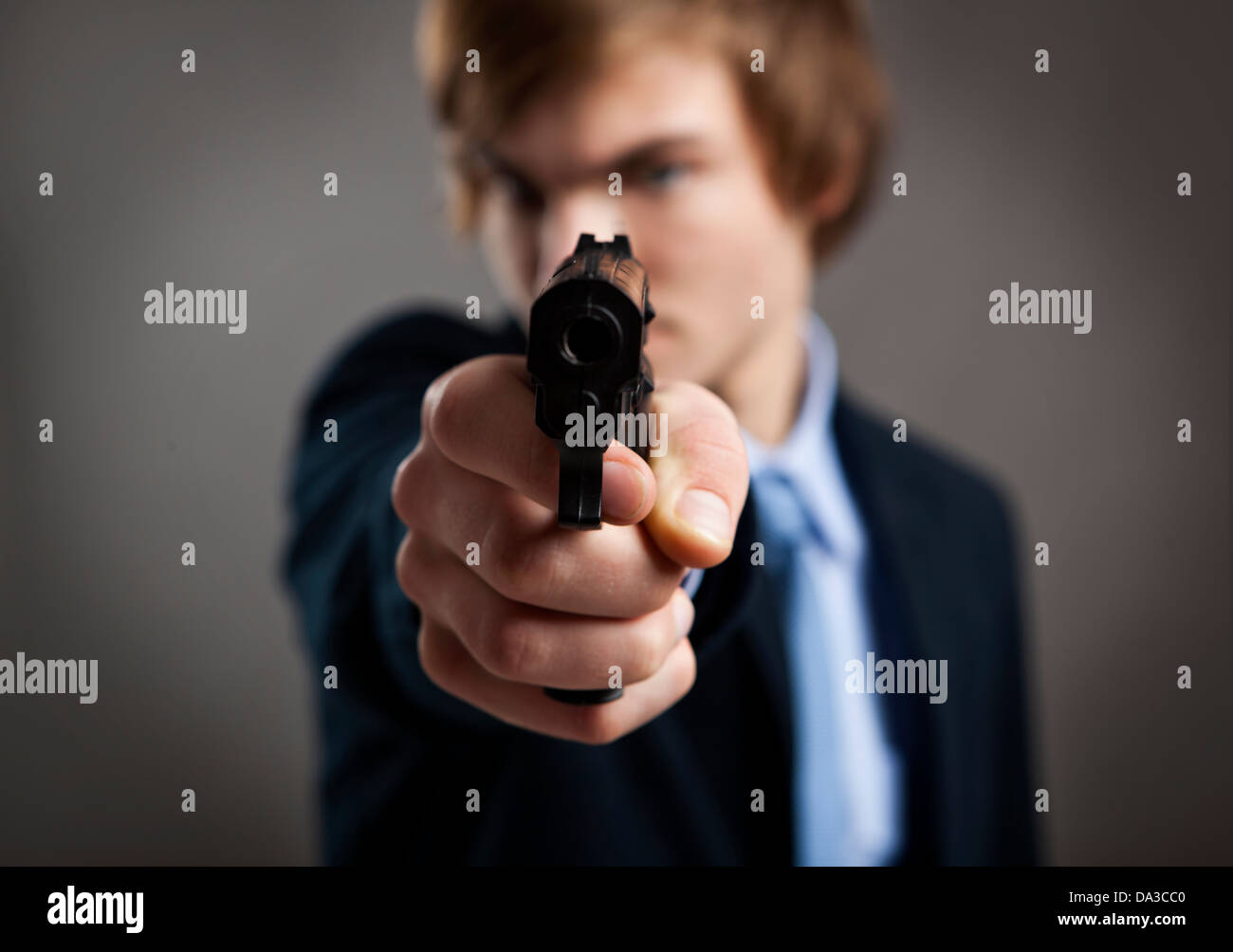 Stressed businessman holding and pointing a gun to the camera Stock Photo