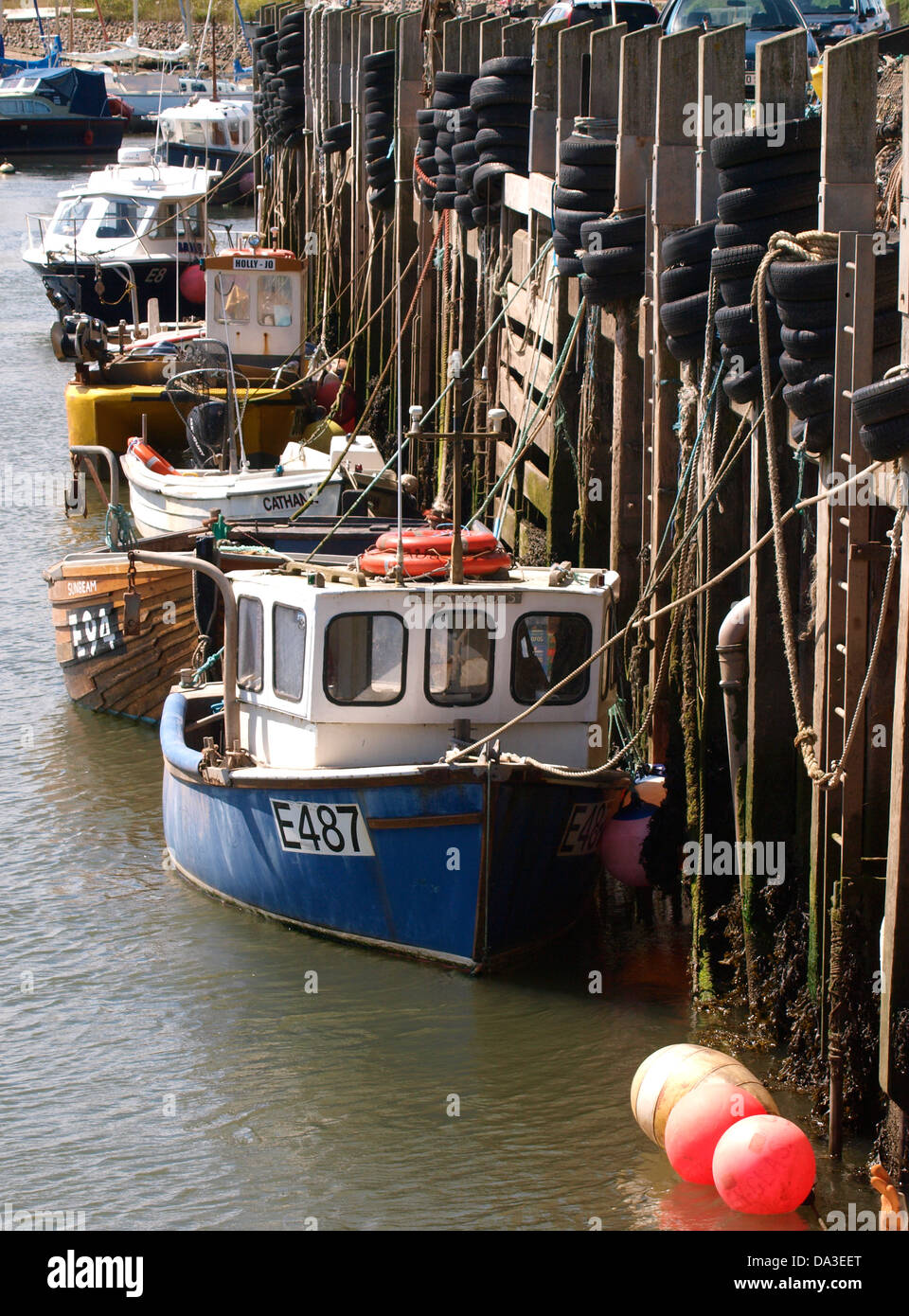 Small commercial fishing boats moored against the harbour wall, Axmouth