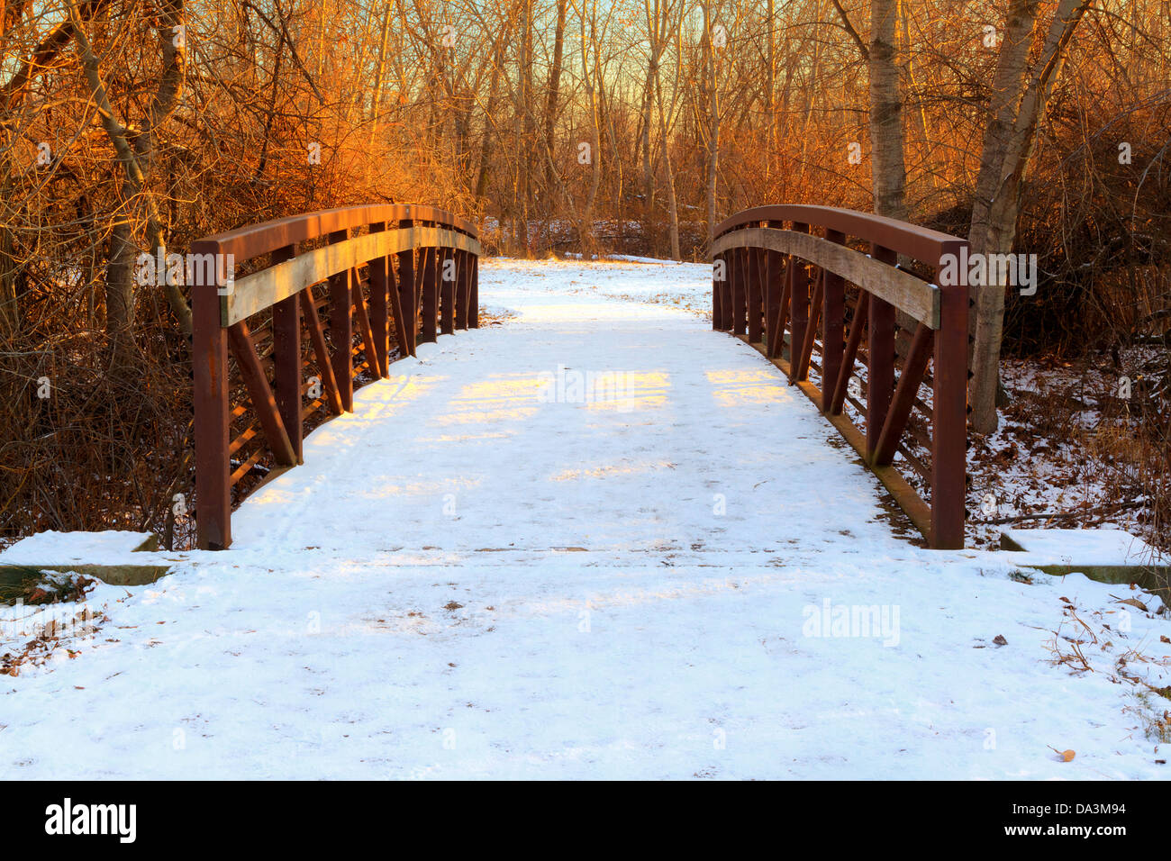 Symmetrical view of pedestrian bridge over creek in downtown Eagle, Idaho, by Boise River on winter evening Stock Photo