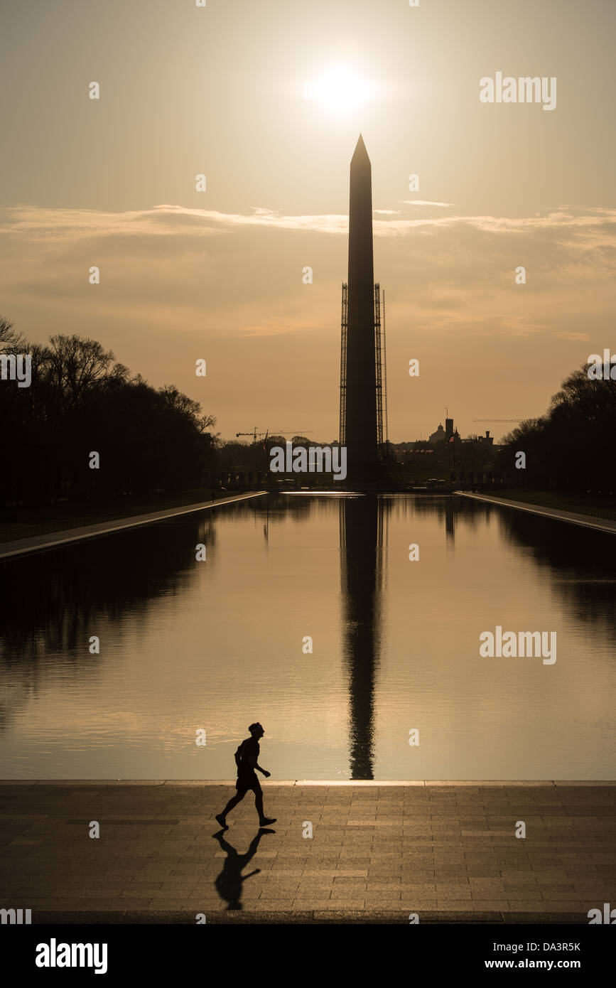 WASHINGTON DC, USA - The early morning sun silhouettes the Washington Monument on the Reflecting Pool in Washington DC. Scaffolding surrounds the Monument part of the way up. Stock Photo