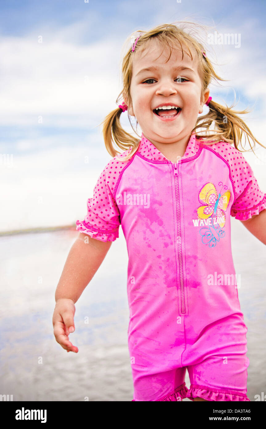 Little girl running on the beach laughing blond two year old toddler