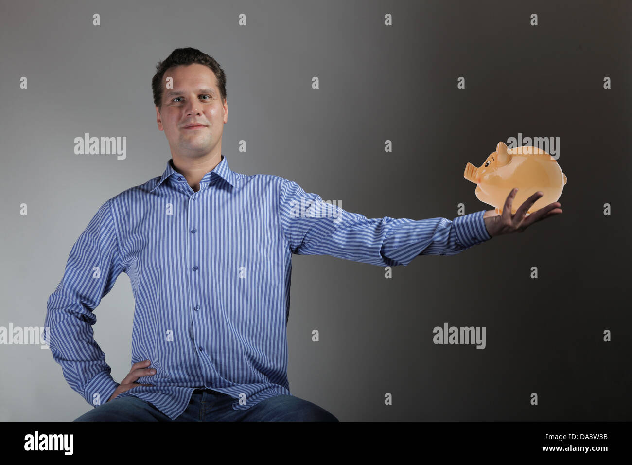 happy man holding a piggy bank gray background Stock Photo - Alamy