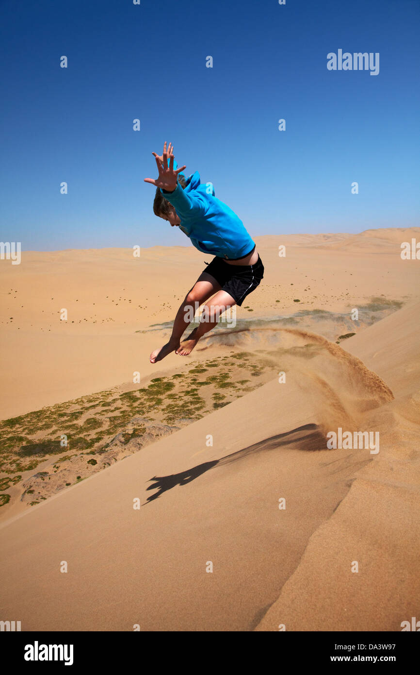 Boy jumping off sand dune, NamibNaukluft National Park, near Sandwich