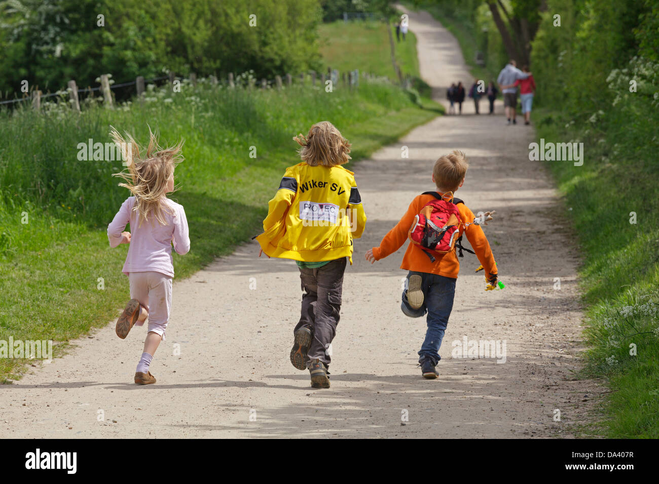 three children running along a path Stock Photo