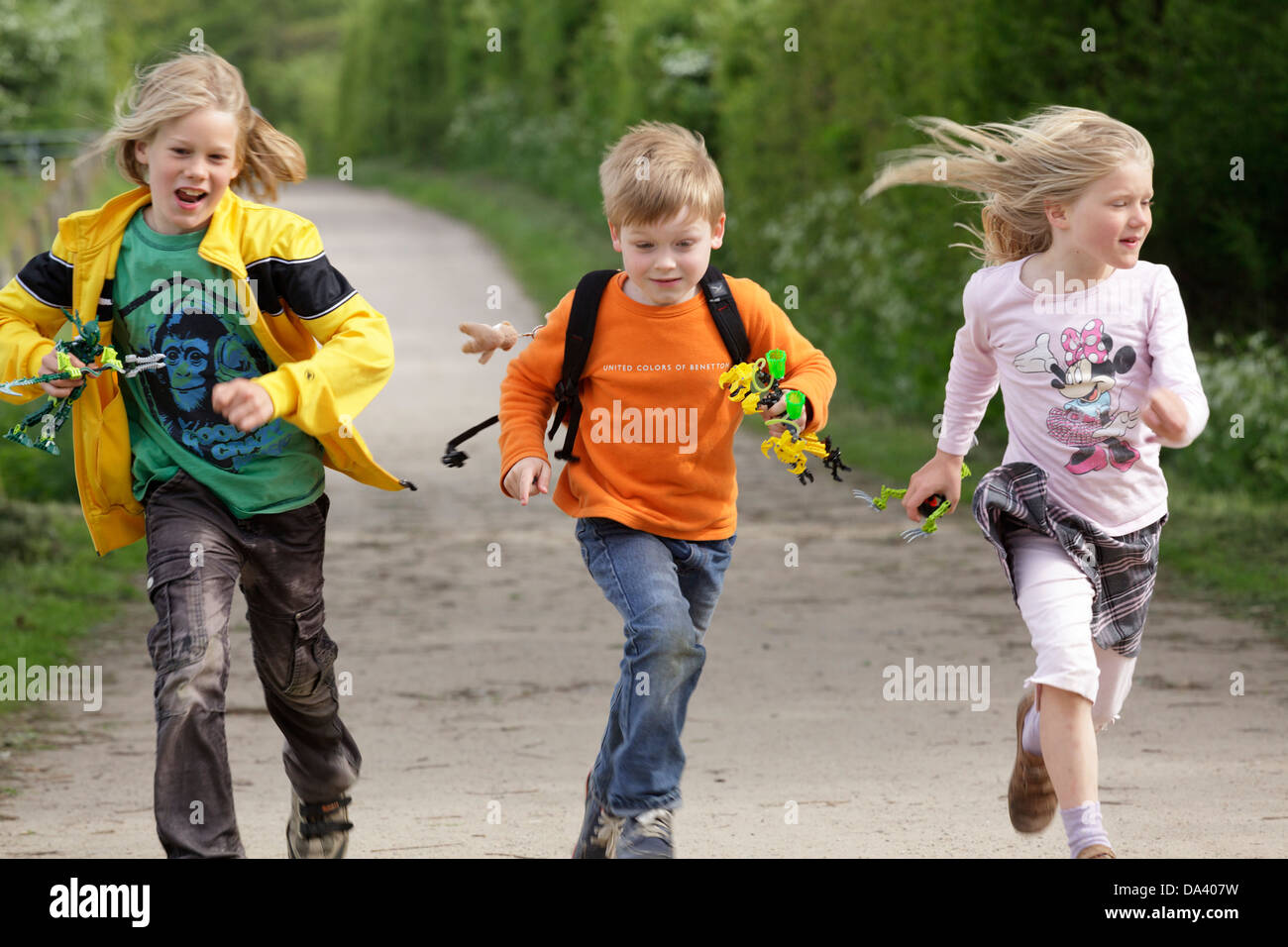three children running along a path Stock Photo