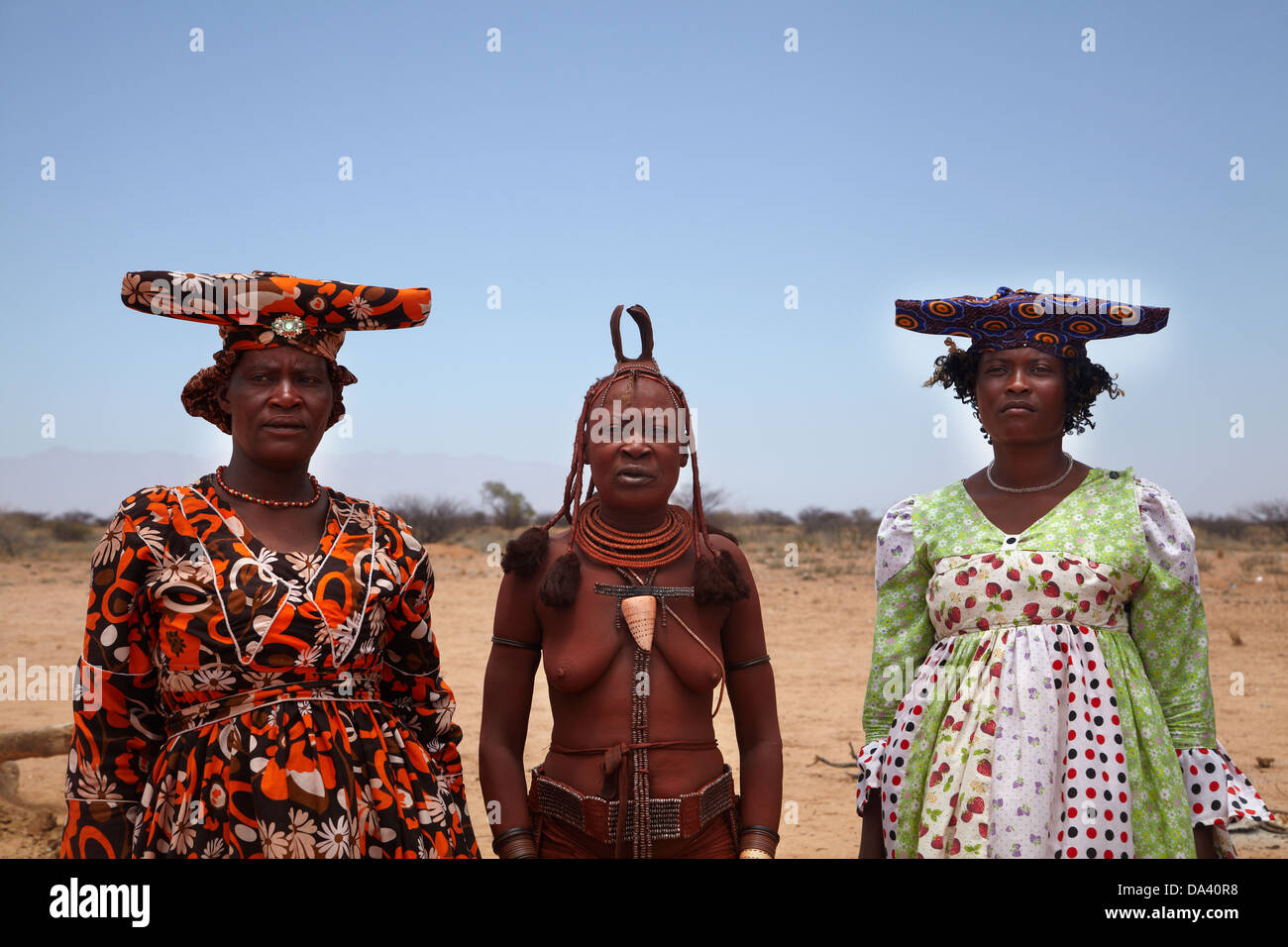 Herero women and Himba woman (centre) in traditional dress, near Uis, Namibia, Africa Stock Photo