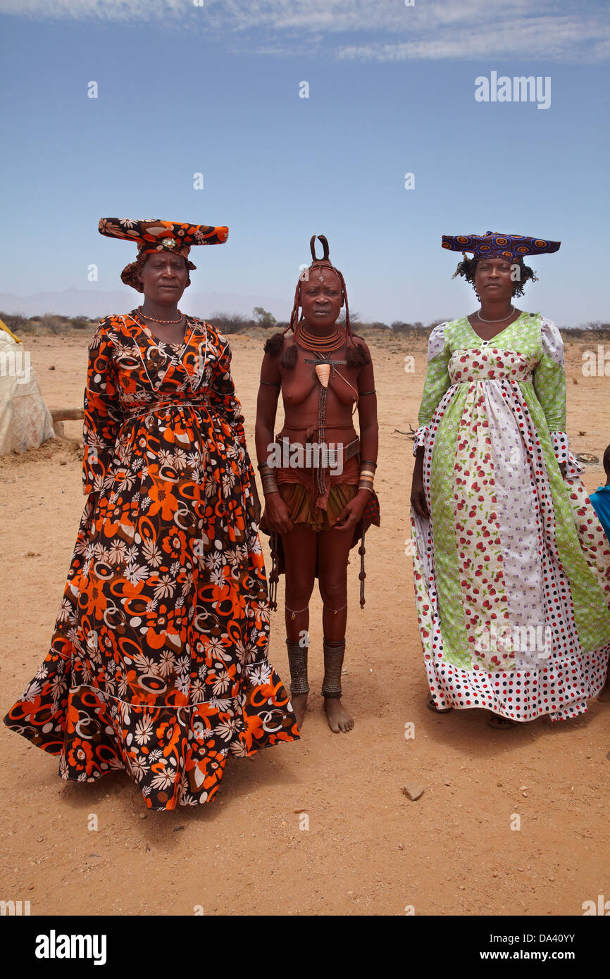 Herero women and Himba woman (centre) in traditional dress, near Uis, Namibia, Africa Stock Photo