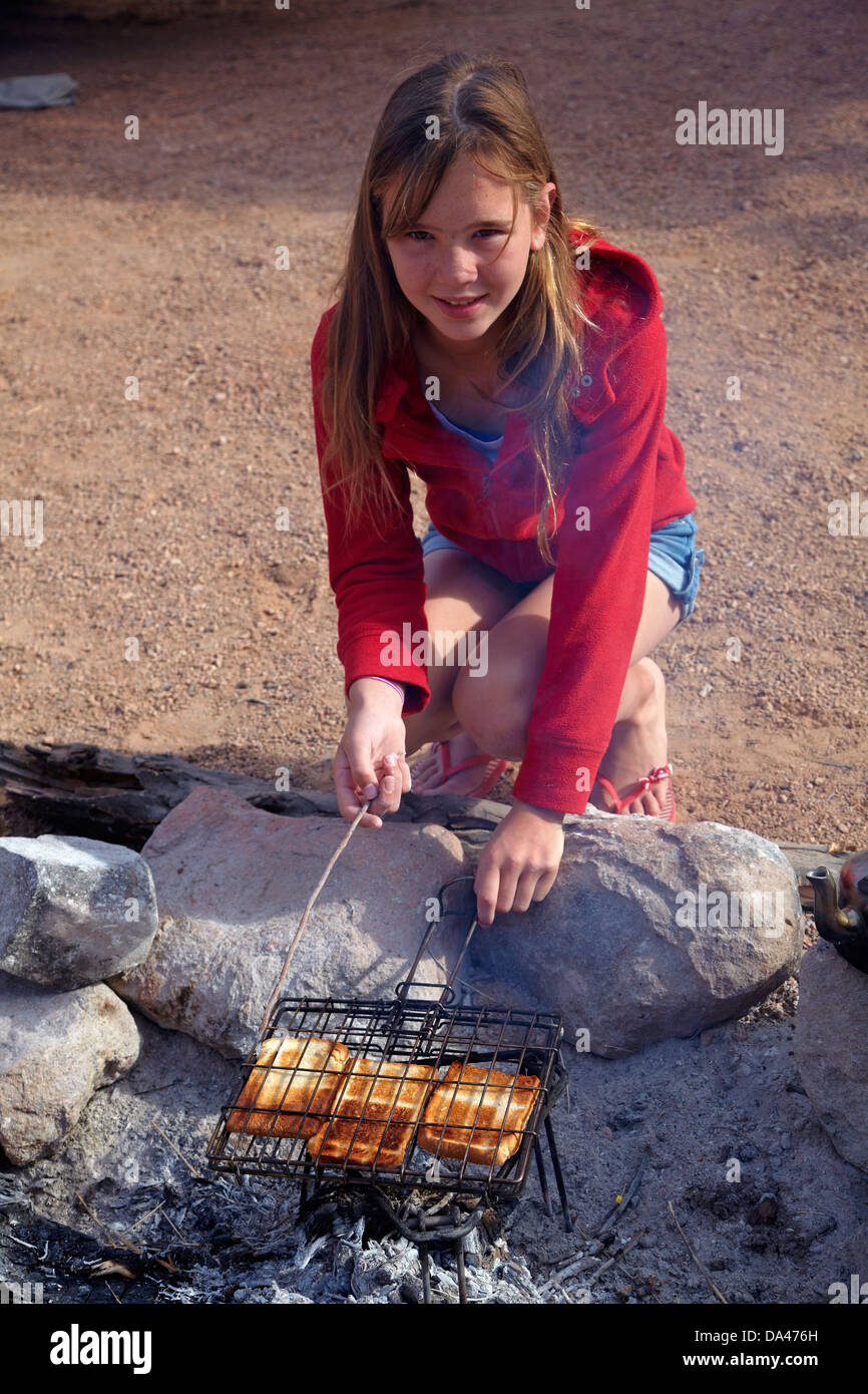 Girl cooking toast on a campfire at campsite at Mowani Mountain Camp, near Twyfelfontein, Damaraland, Namibia, Africa Stock Photo