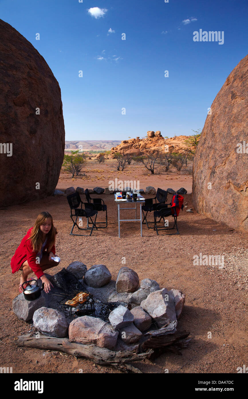 Girl cooking toast on a campfire at campsite at Mowani Mountain Camp, near Twyfelfontein, Damaraland, Namibia, Africa Stock Photo