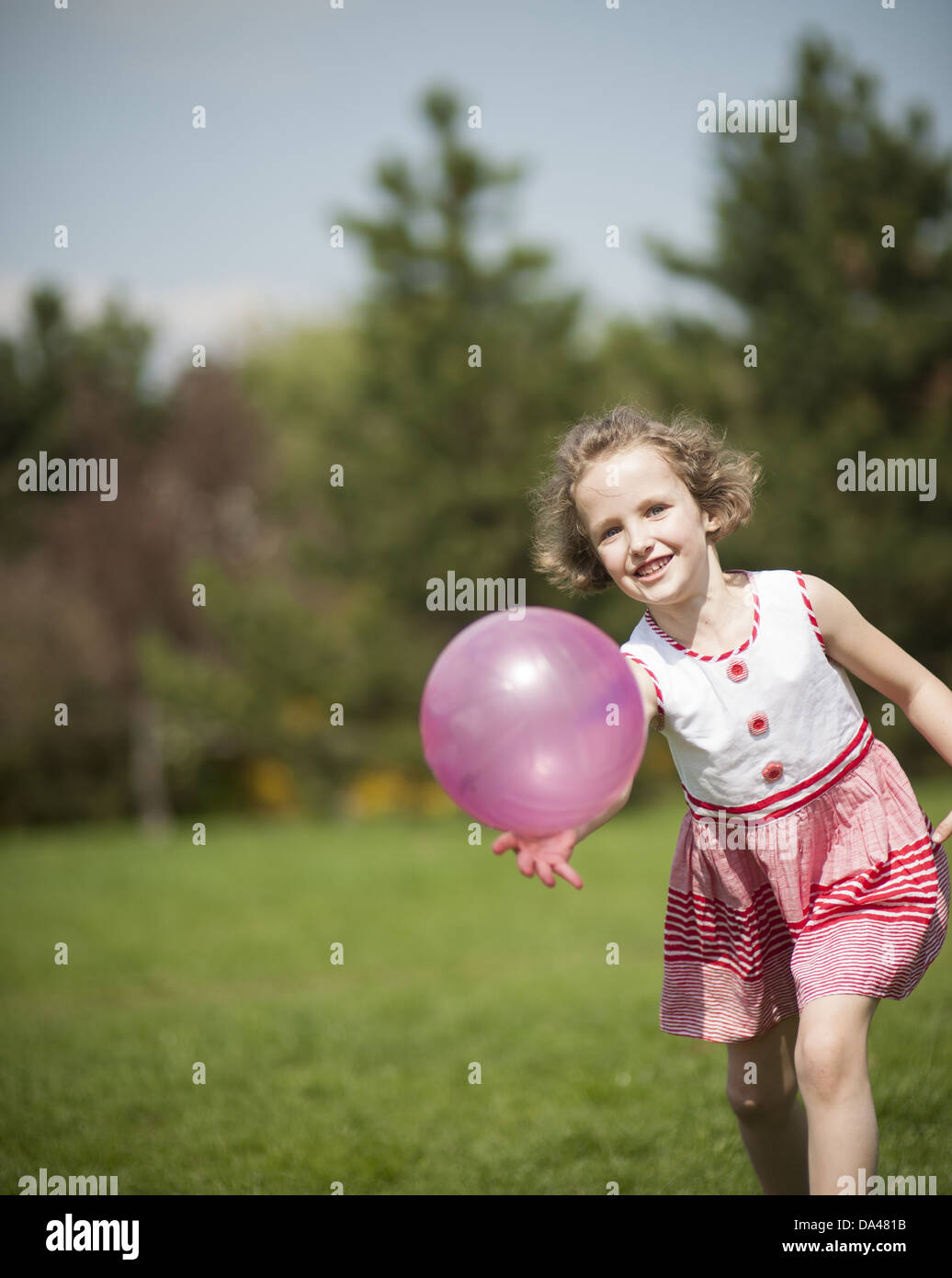 Young girl playing with purple ball in the park Stock Photo