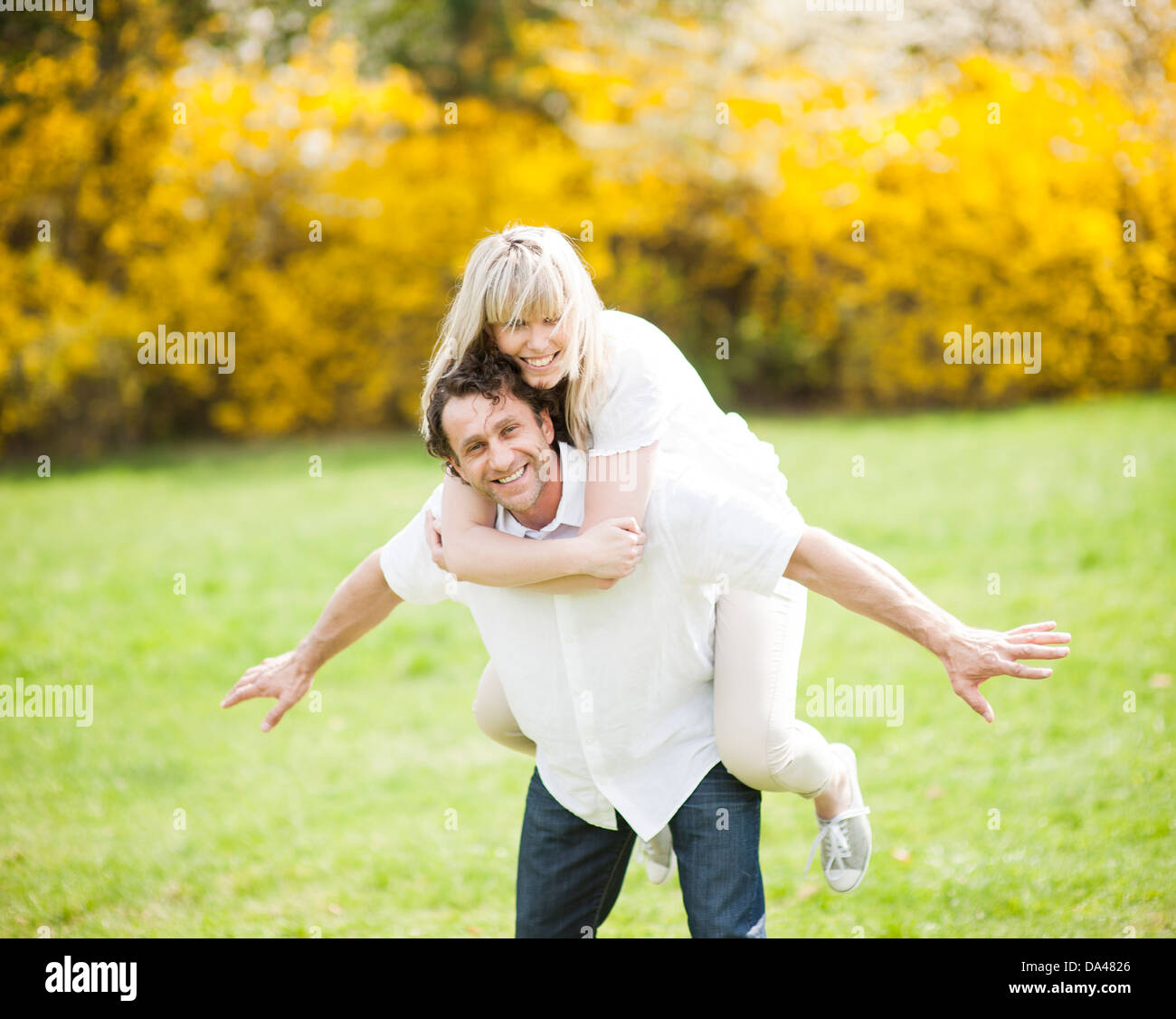 Man piggybacking woman in park Stock Photo