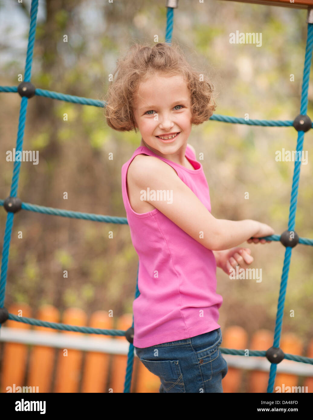 Young girl on climbing net turning to face camera Stock Photo