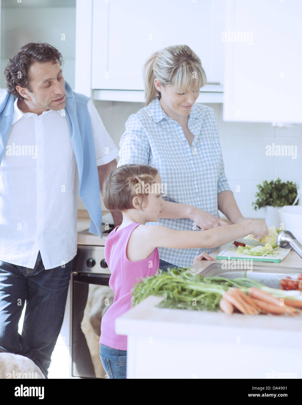 Family making a healthy salad in the kitchen Stock Photo