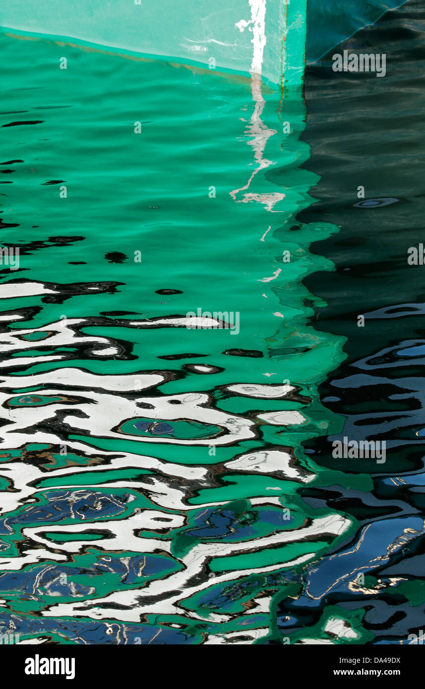 Green hull of a boat with artistic reflection in the water Stock Photo