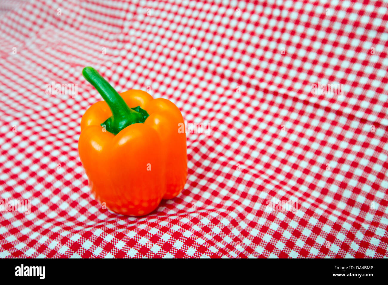 Orange Bell Pepper against red and white chequered cloth Stock Photo